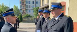 Zdjęcie wykonano na placu przed budynkiem Komendy Powiatowej PSP w Będzinie. Komendant Powiatowy mł. bryg. Arkadiusz Spera składa gratulacje trzem funkcjonariuszom , którzy awansowali na stopnie aspiranckie. Wszyscy ubrani są w mundury wyjściowe.