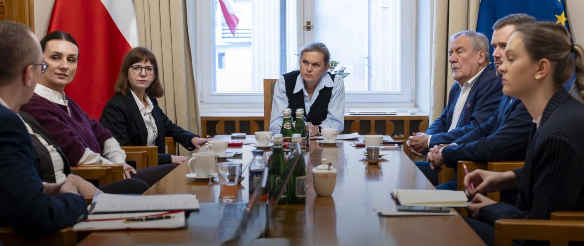 kilka osób siedzi przy stole i rozmawia