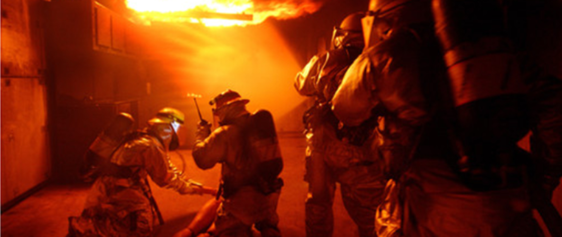 Zdjęcie przedstawia czterech strażaków podczas ćwiczeń praktycznych w zakresie działań gaśniczych oraz ewakuacji osoby poszkodowanej