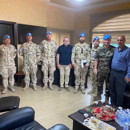 Grupa żołnierzy, w tym jedna kobieta, oraz dwóch cywili stoi w półokręgu pozując do zdjęcia