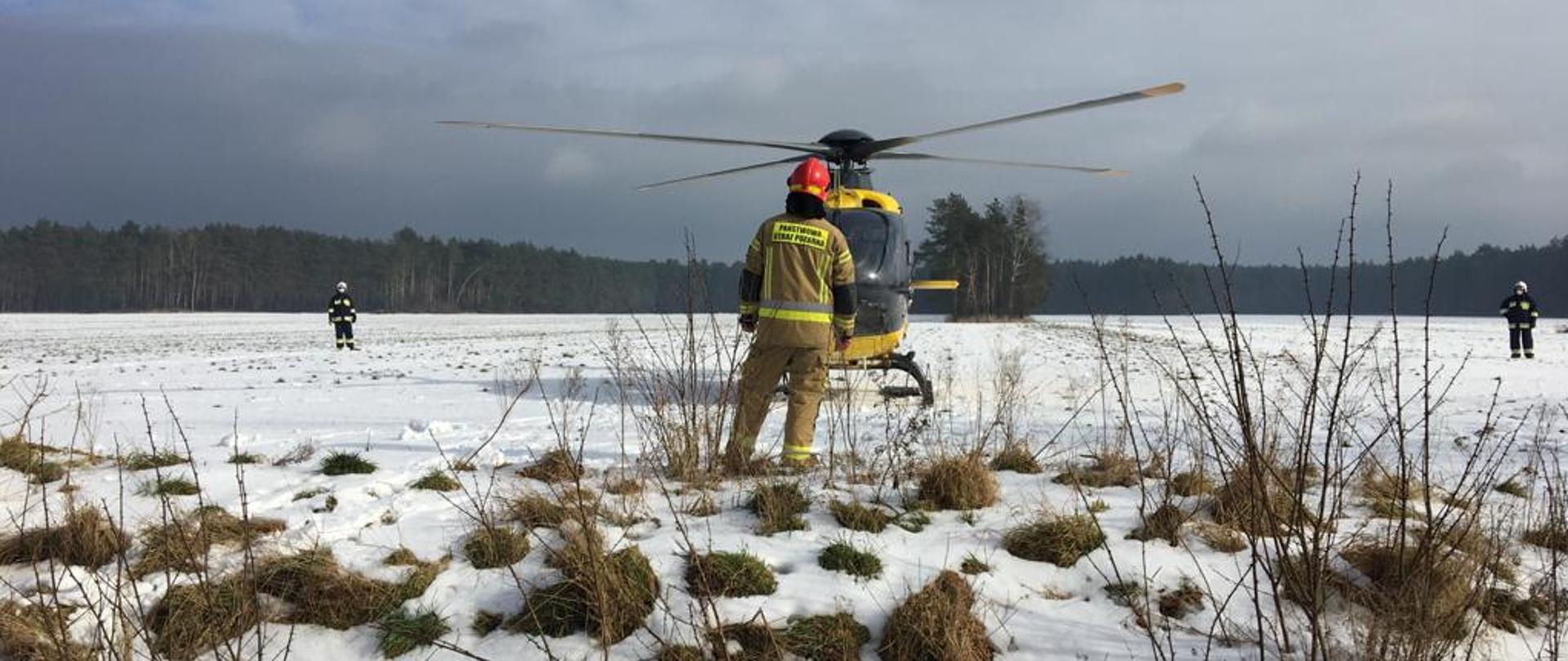 Strażak, na tle śmigłowiec LPR