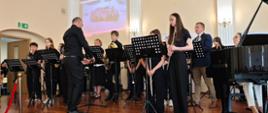 Wykonawcy przy instrumentach na scenie w sali koncertowej podczas Koncertu końcoworocznego wpisującego się w szmaragdowy Jubileusz lublinieckiej szkoły muzycznej