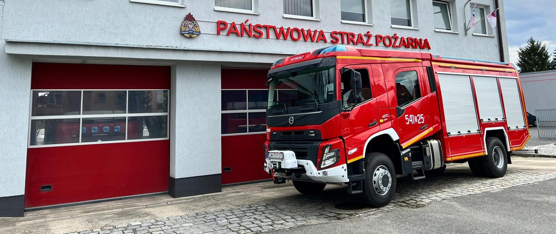 Ciężki samochód gaśniczy na tle budynku komendy powiatowej