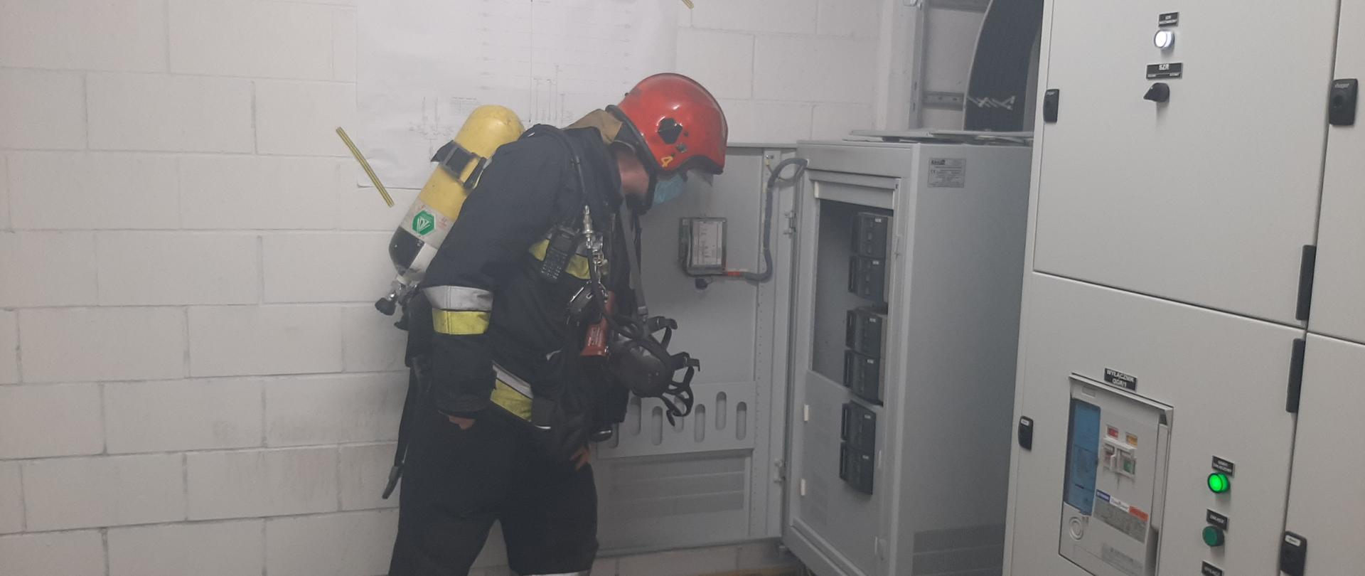 Na zdjęciu strażak w pełnym zabezpieczeniu sprawdzający miejsce w którym doszło do pożaru