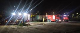 Pora nocna, widoczne pojazdy gaśnicze, torowisko oraz wagon, działający ratownicy. oświetlony teren