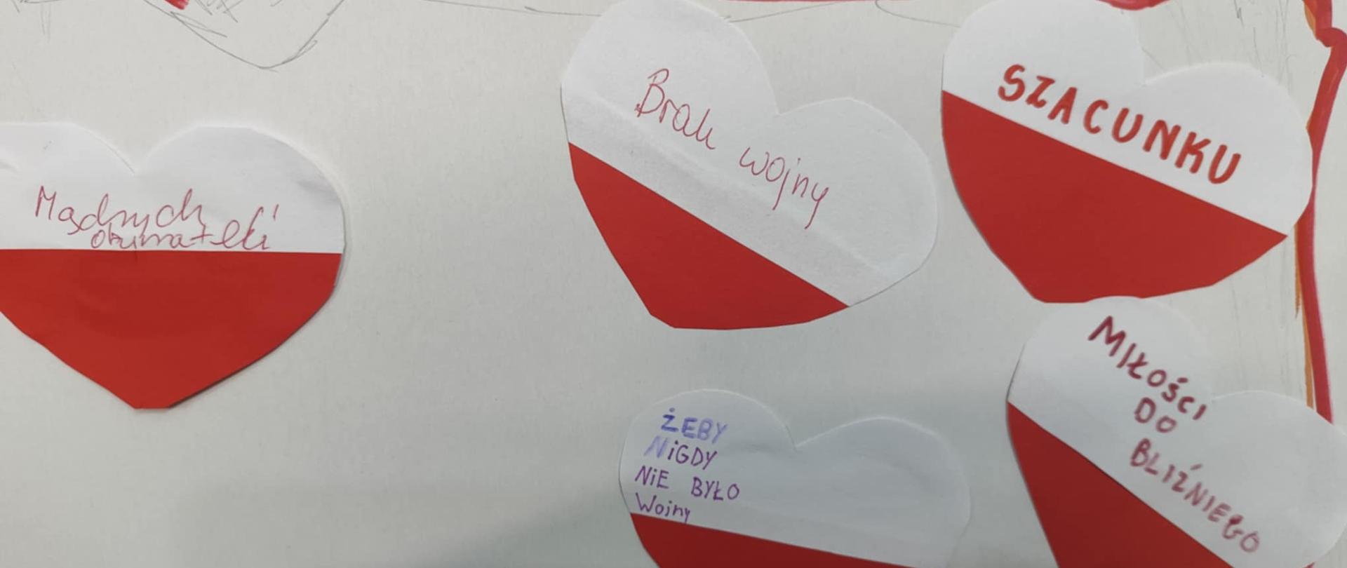Na zdjęciu fragment zarysu granic Polski. W górnym prawym rogu pięć przyklejonych biało-czerwonych serc z napisami: na pierwszym napis Szacunku, na drugim napis Miłości do bliźniego, na trzecim żeby nigdy nie było wojny, na czwartym Brak wojny a na piątym Mądrych obywateli.