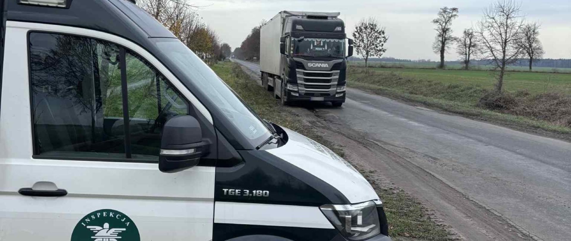 Na pierwszym planie widoczny pojazd ITD, za nim zaparkowany przy drodze polnej, pojazd ciężarowy.