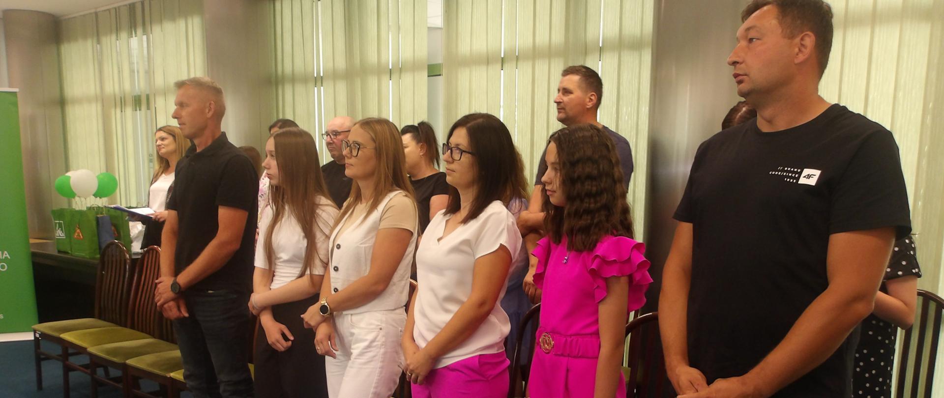 Laureaci, rodzice i opiekunowie stoją w sali konferencyjnej podczas uroczystego podsumowania etapu regionalnego konkursu dla Dzieci na Rymowankę o Bezpieczeństwie w Gospodarstwie Rolnym „Wioski bez troski”.