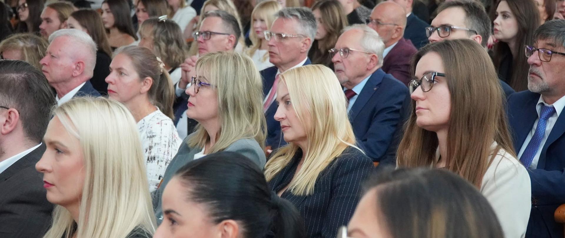 kilkadziesiąt osób siedzi na Aulii na uniwersytecie 