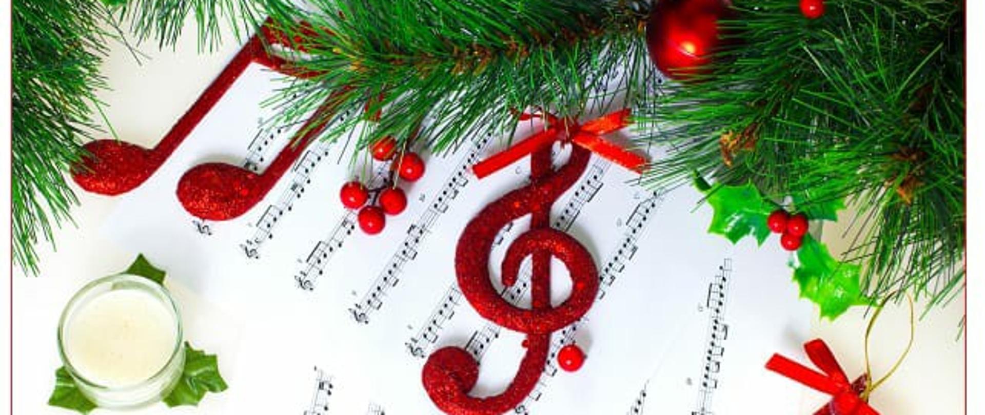 Kartka z życzeniami świątecznymi w formie fotografii fragmentu stołu świątecznego. Widoczny jest na niej fragment obrusu w kolorze kremowym (tło), stroika z naturalnego igliwia przystrojonego czerwonymi bombkami, nutkami i kluczem wiolinowym i fragmenty okrągłych serwet wykonanych na szydełku. Na środku kartki wstawione jest logo szkoły, a pod nim zamieszczone są życzenia. Karta wykończona jest delikatną białą ramką.