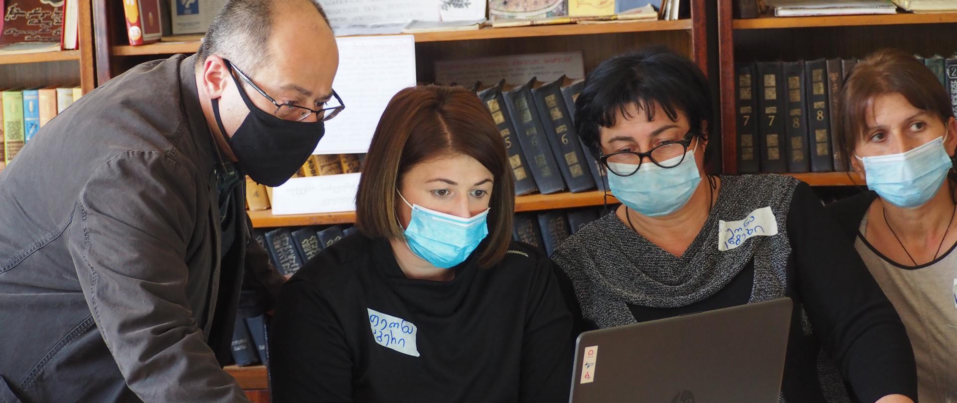 trwa szkolenie z obsługi komputera - 4 osoby patrzą w monitor komputera