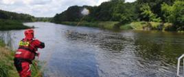 Strażak rzuca rzutką ratowniczą do rzeki
