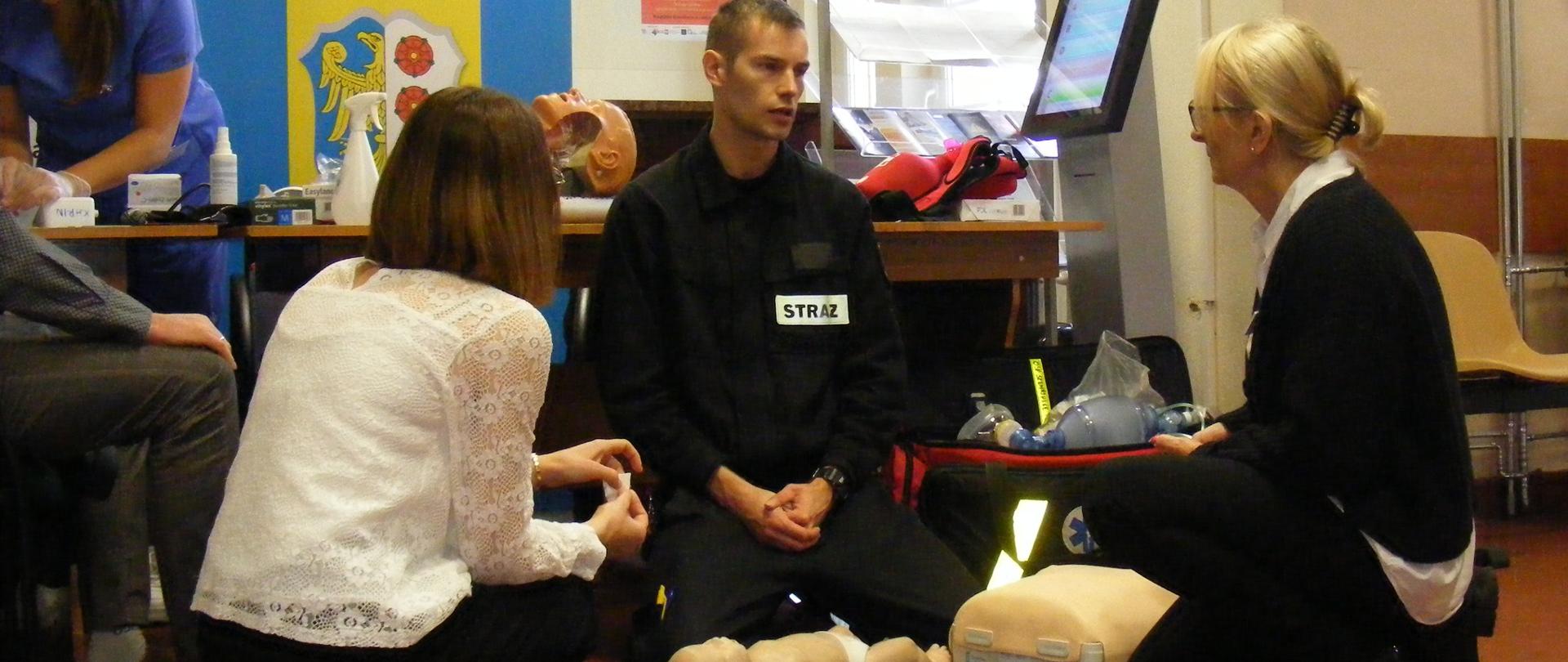 Strażak podczas pokazów ratownictwa medycznego - pokazuje udzielanie pomocy niemowlakowi.