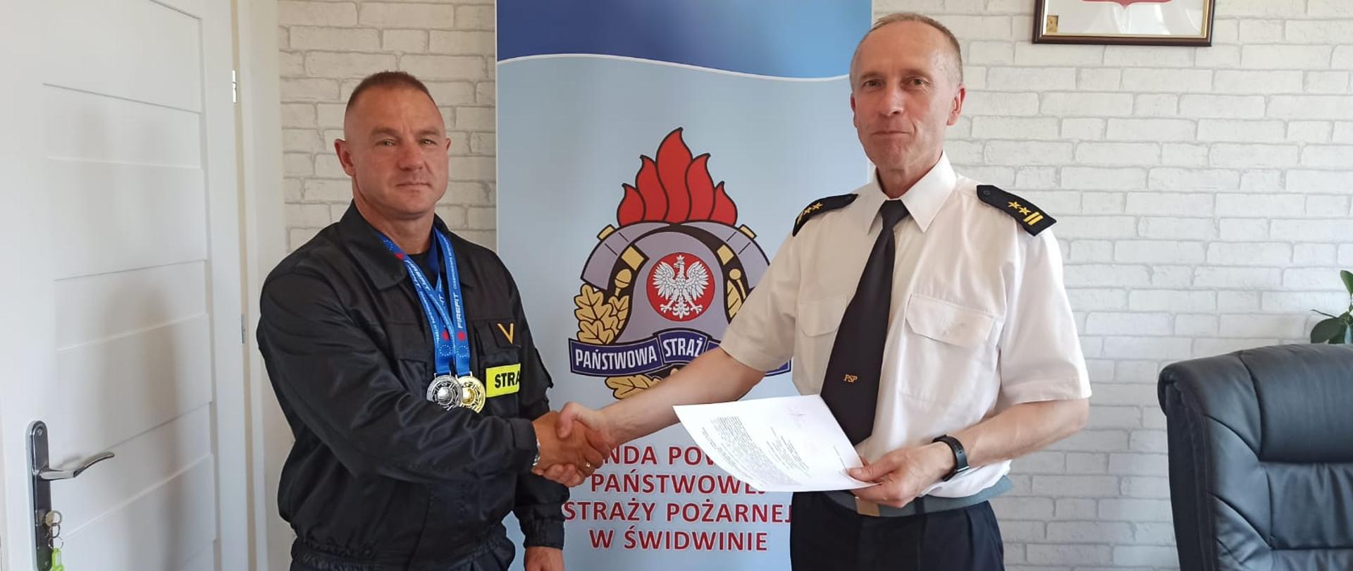 Zdjęcie przedstawia wręczenie decyzji przez komendanta powiatowego zasłużonemu sportowcu. 