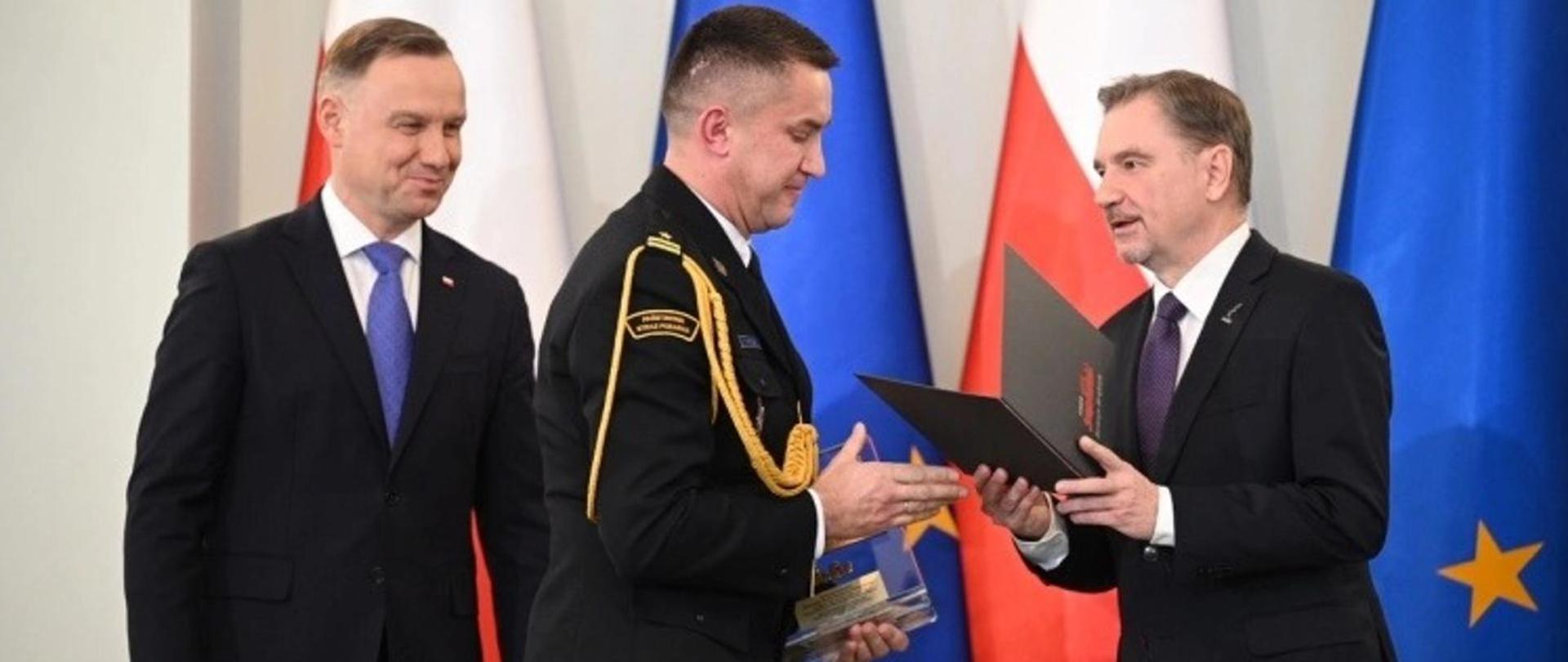 Na zdjęciu widać Prezydenta RP, Komendanta KP PSP i osobę wręczającą. 
