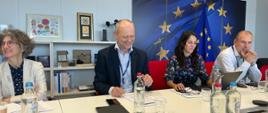 Dyrektor Generalny DG REGIO w Komisji Europejskiej Normunds Popens siedzi przy stole i uśmiecha się, obok niego siedzą jego współpracownicy