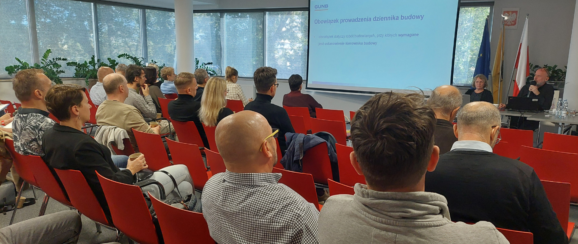 Na zdjęciu sala szkoleniowa – uczestnicy siedzą przy stołach, słuchają prelegenta.