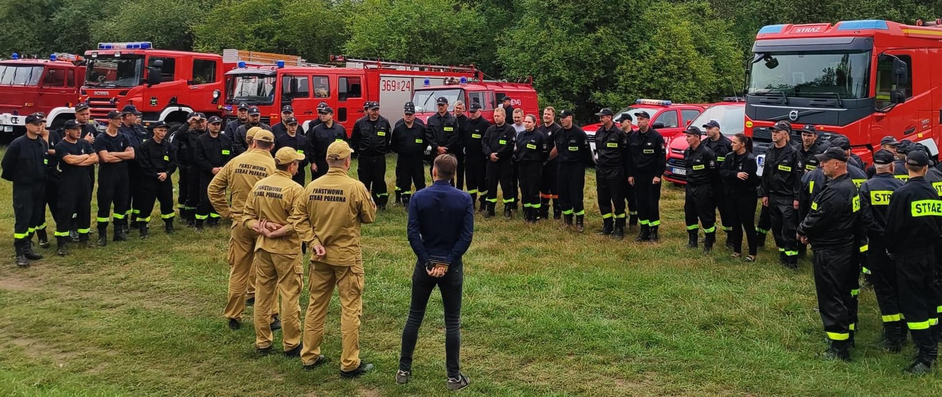 Zdjęcie grupowe uczestników ćwiczeń w tle widoczne pojazdy ratowniczo-gaśnicze