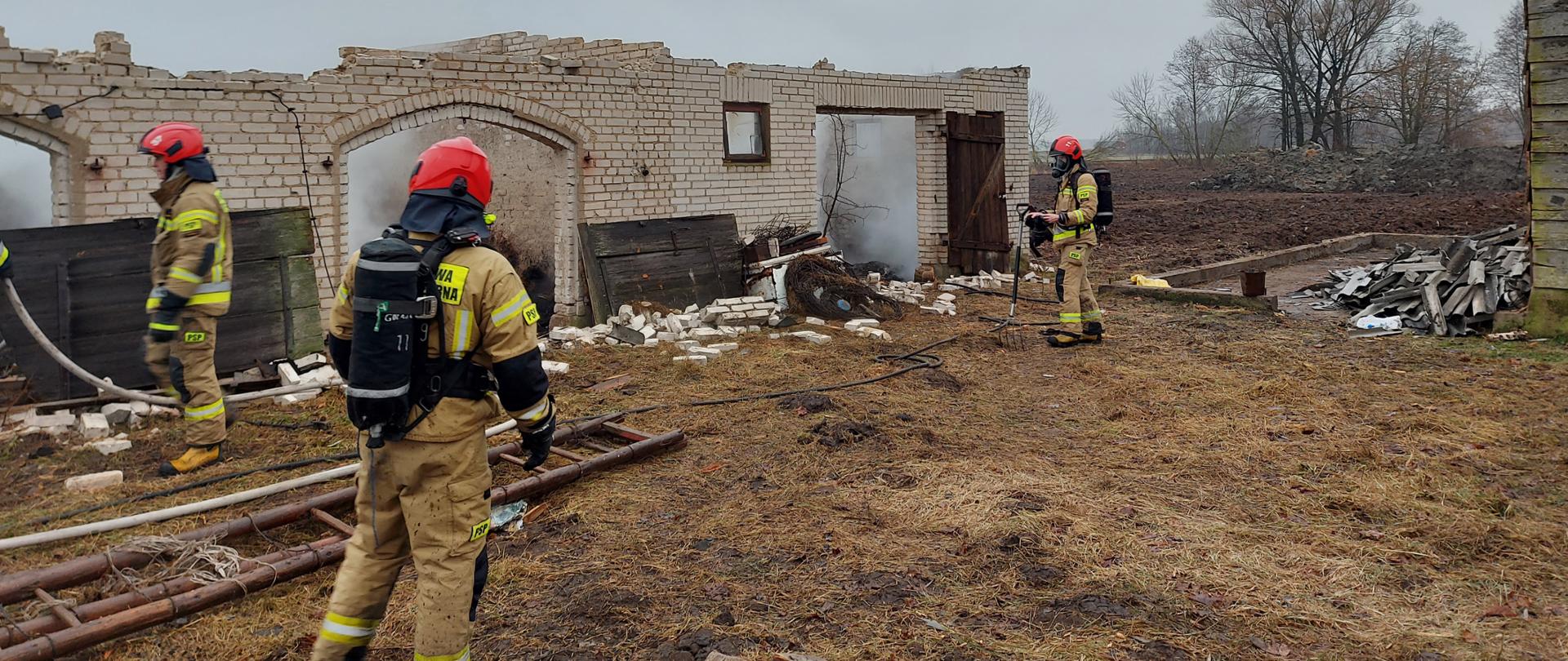 Strażacy PSP pracują przy zawalonym budynku gospodarczym.