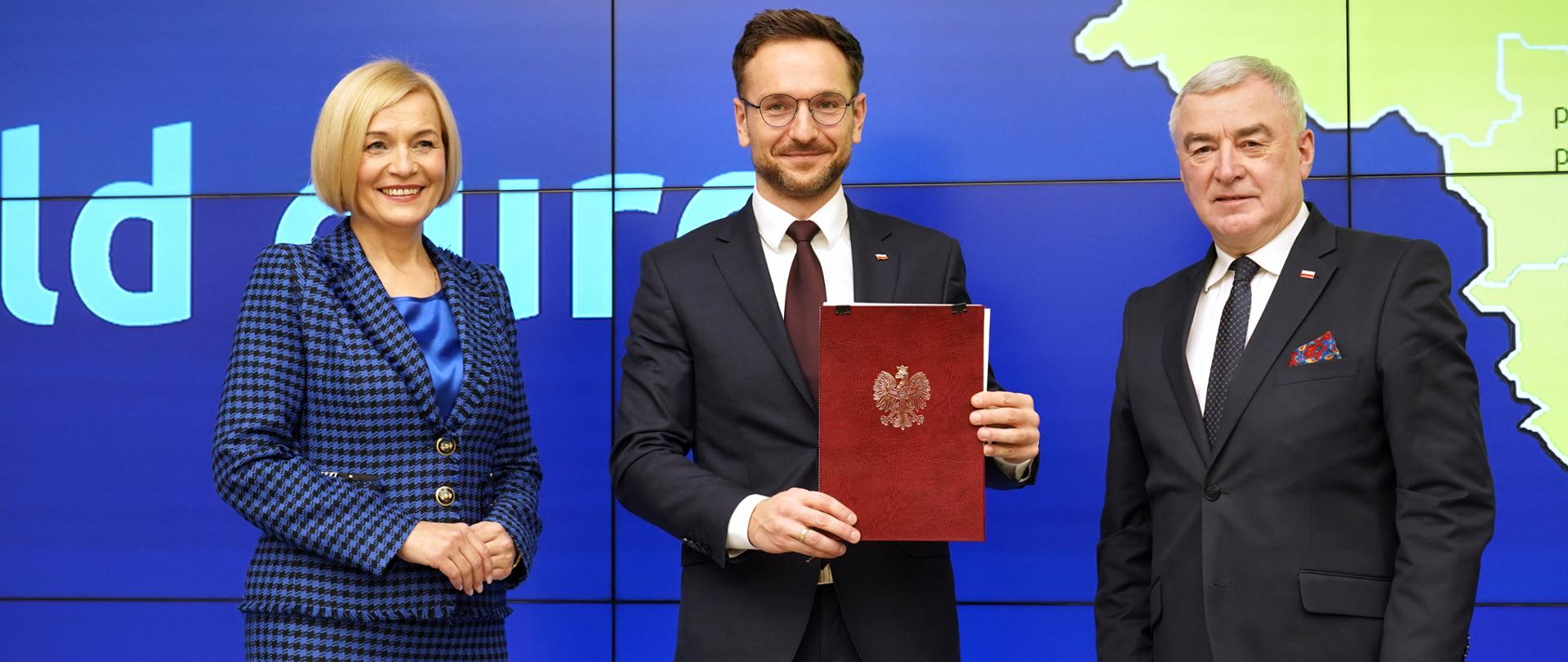 Od lewej wicemarszałek Renata Janik, wiceminister Waldemar Buda i marszałek Andrzej Bętkowski pozują do zdjęcia na scenie