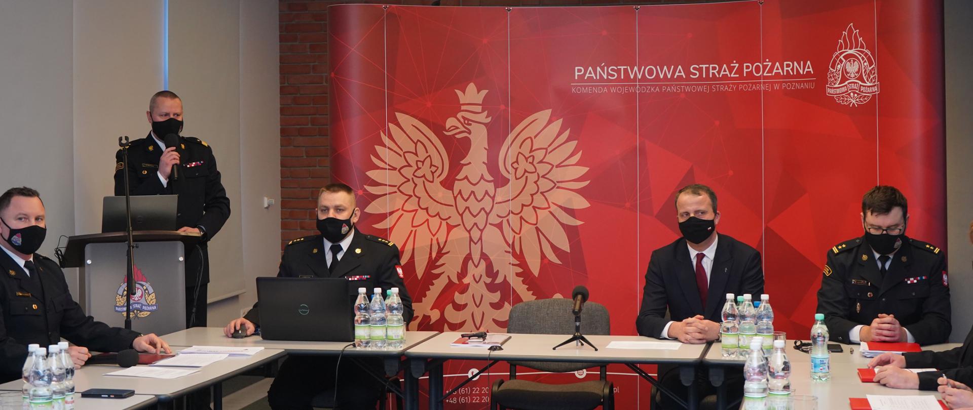 nadbrg. Dariusz Matczak otwierający naradę, za stołem prezydialnym siedzą Wojewoda Wielkopolski oraz dwaj zastępcy komendanta wojewódzkiego PSP