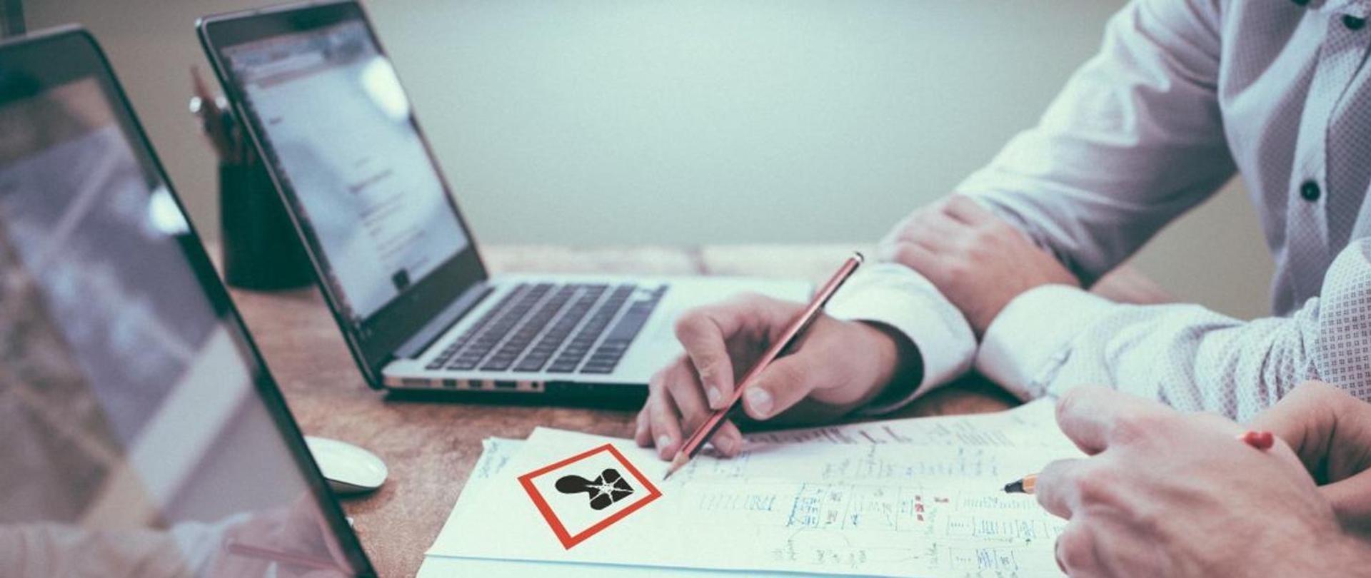 Pracownik biurowy z ołówkiem w ręku wypełniający dokument z widocznym piktogramem: Czynniki rakotwórcze, mutagenne lub reprotoksyczne. 