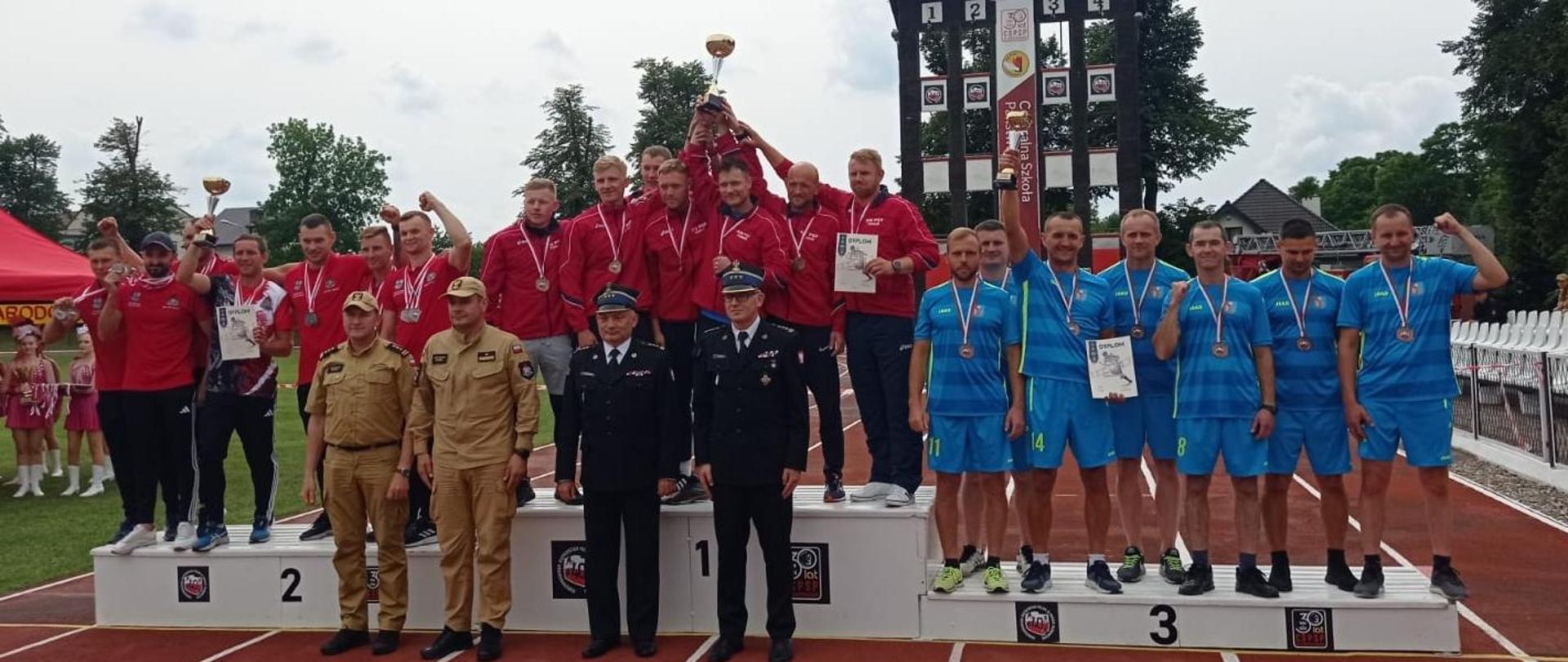 Zdjęcie przestawia podium wraz z drużynami które zajęły kolejno pierwsze, drugie i trzecie miejsce w ćwiczeniu bojowym. Na najniższym stopniu podium znajduje się drużyna z Krosna.