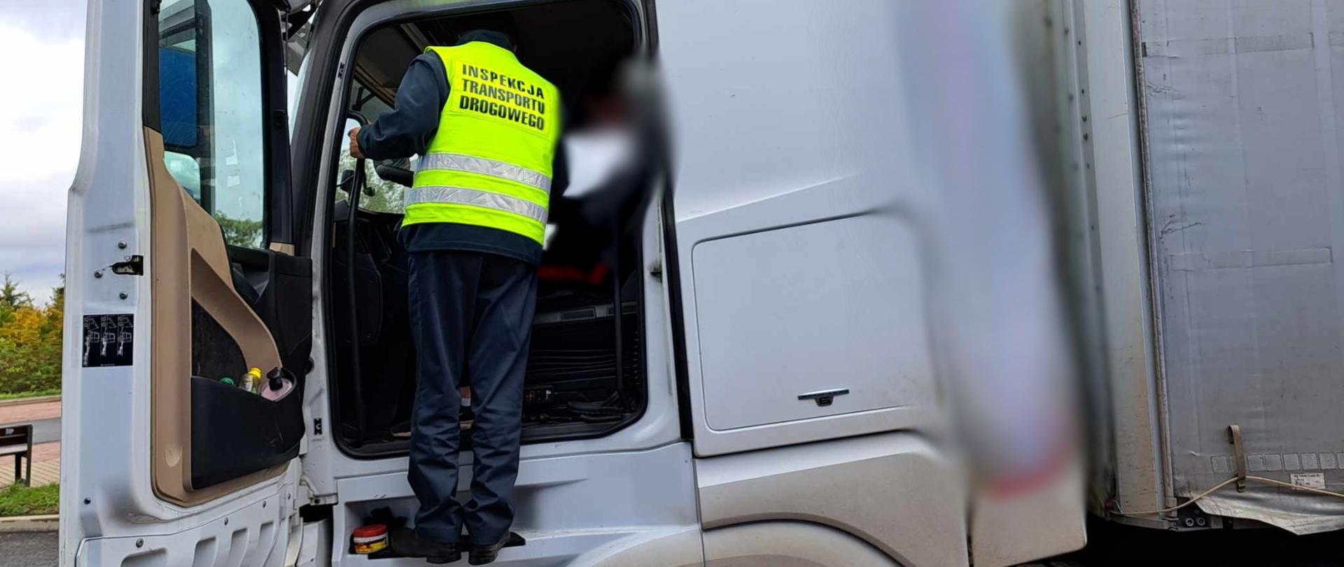 Inspektor dolnośląskiej Inspekcji Transportu Drogowego kontroluje tachograf w zatrzymanej ciężarówce.