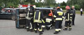 Strażacy ćwiczący uwalnianie osoby znajdującej się przewróconym pojeździe