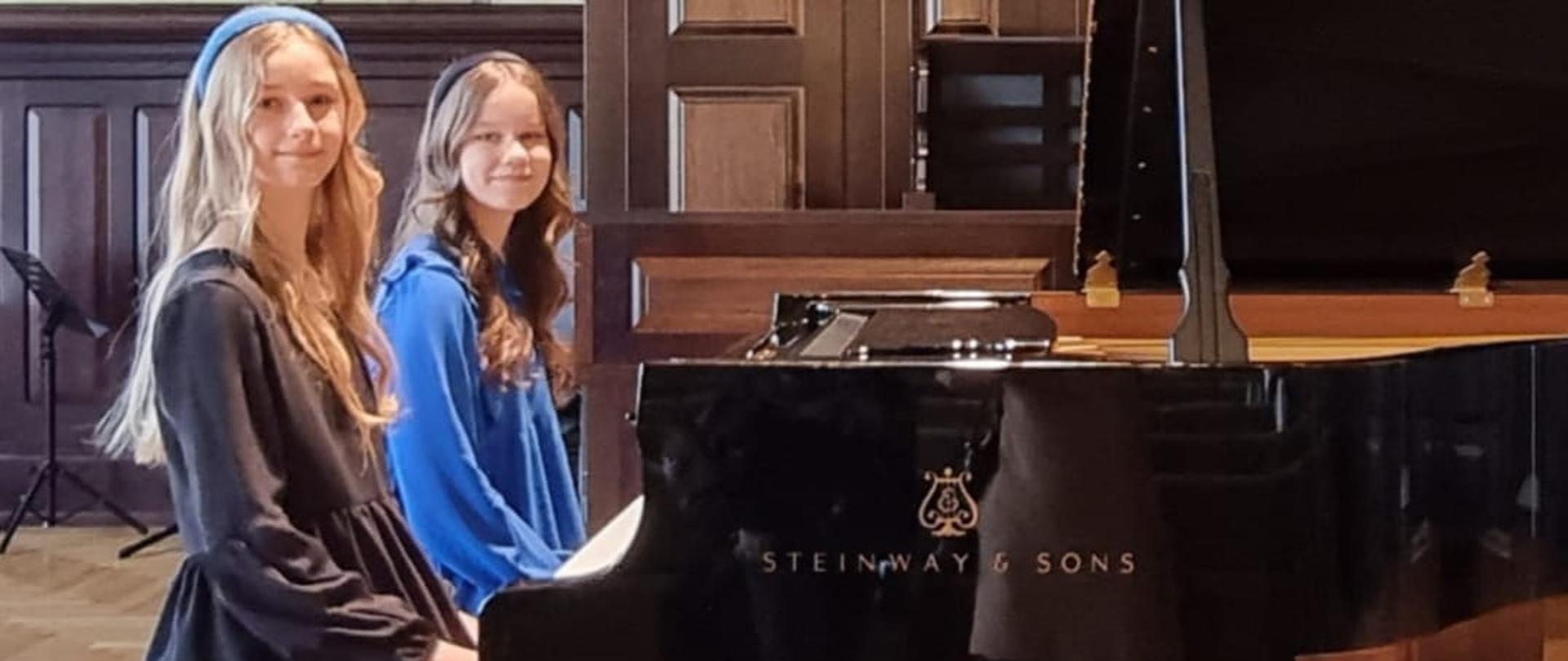 na zdjęciu dwie uczennice siedzące przy fortepianie 