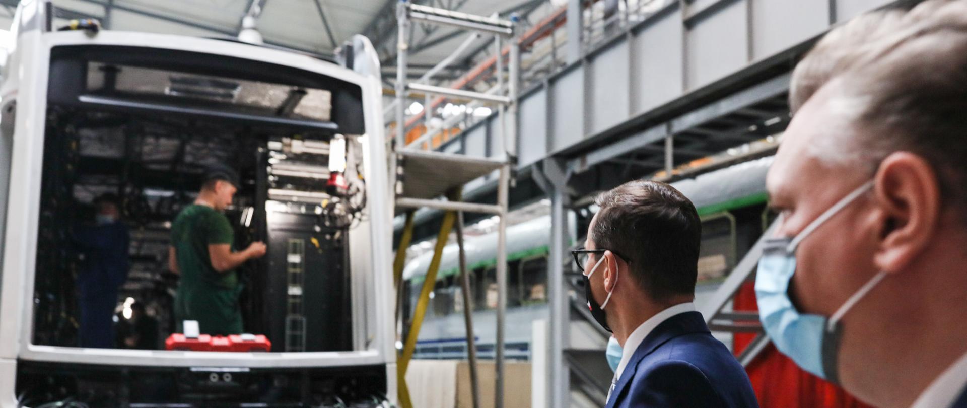 Premier oraz mężczyzna stoją obok tramwaju. 