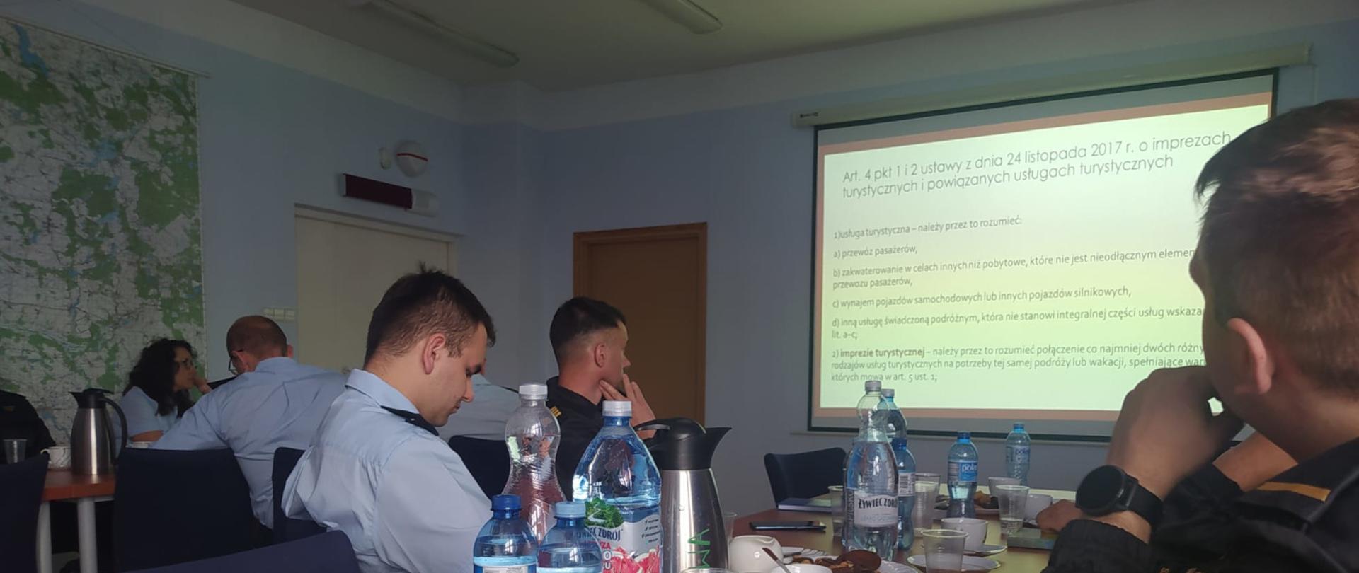 Strażacy patrzą na ekran z prezentacją. 