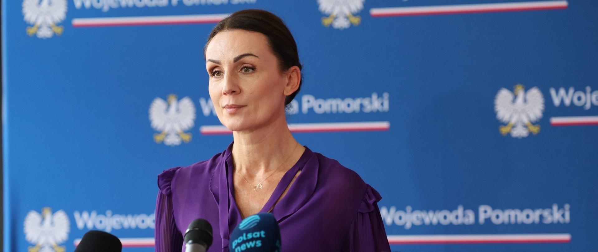 kobieta (wojewoda) stoi przed mikrofonem