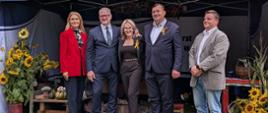 Grupa osób pozuje do zdjęcia na tle stoiska targowego
