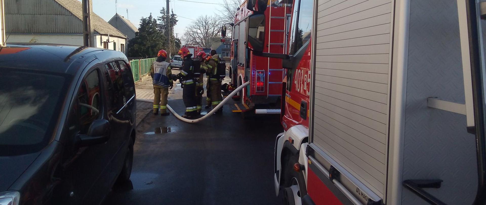 Zdjęcie przedstawia strażaków gaszących pożar zakładu ceramiki w Stróżewie.
W tle budynki i samochody strażackie. 