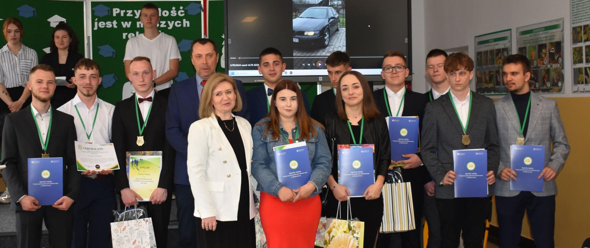 Grupowe zdjęcie uczniów i nauczycieli z dyplomami po zakończeniu akademii.