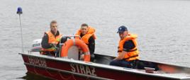 Jezioro lódź strażacy na łodzi w kapokach wraz z funkcjonariuszem policji