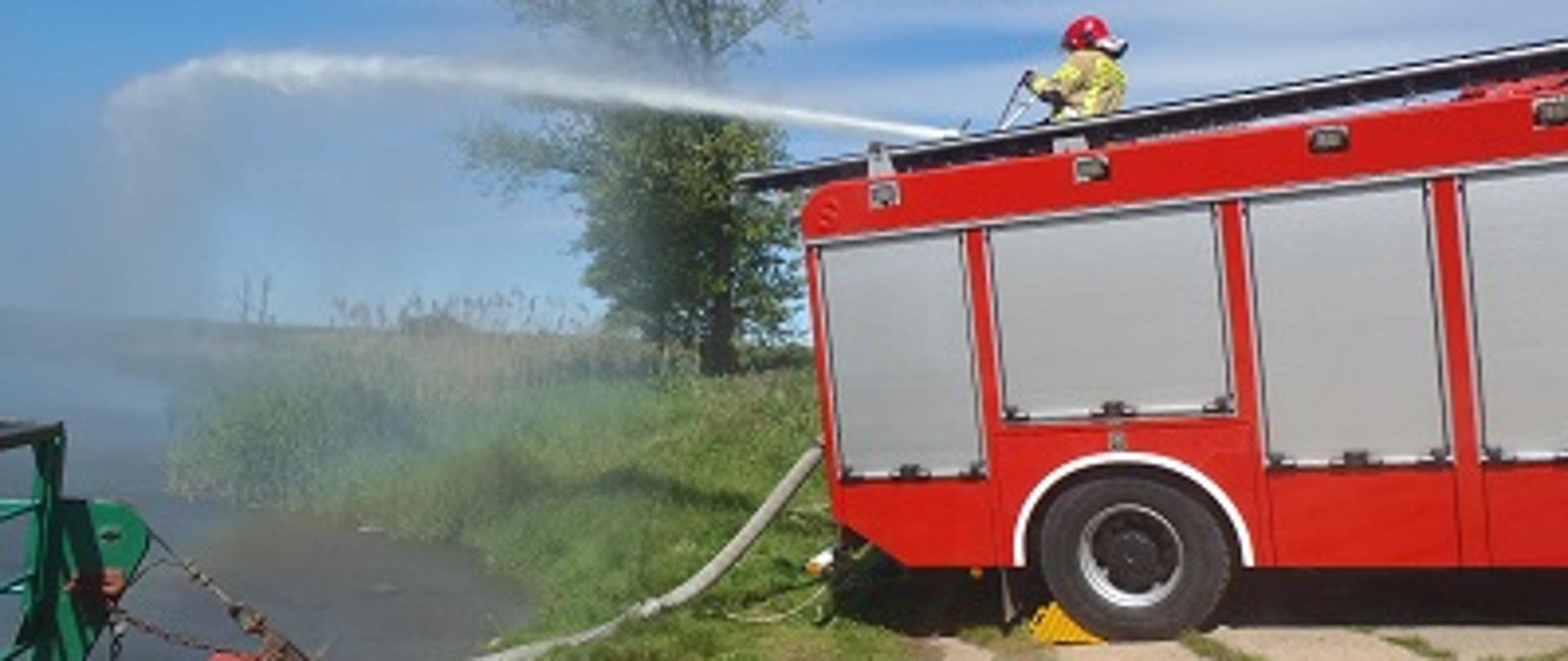 Strażak obsługujący działko wodne z dachu wozu bojowego. 