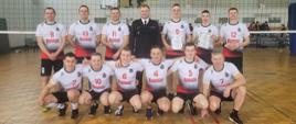 zawodnicy piłki siatkowej z KP PSP Kozienice pozuję do zdjęcia z Komendantem z Kozienic pod siatką na boisku sportowym
