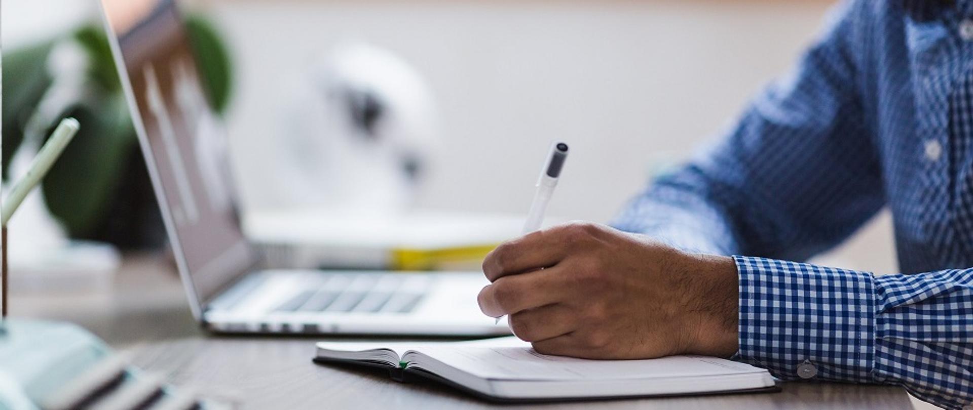 mężczyzna z notesem przy tablecie