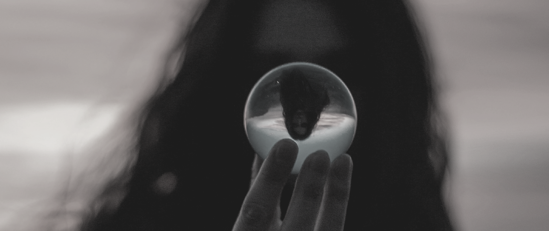 Kobieta z długimi włosami trzymająca przezroczystą kulkę w dłoni. 