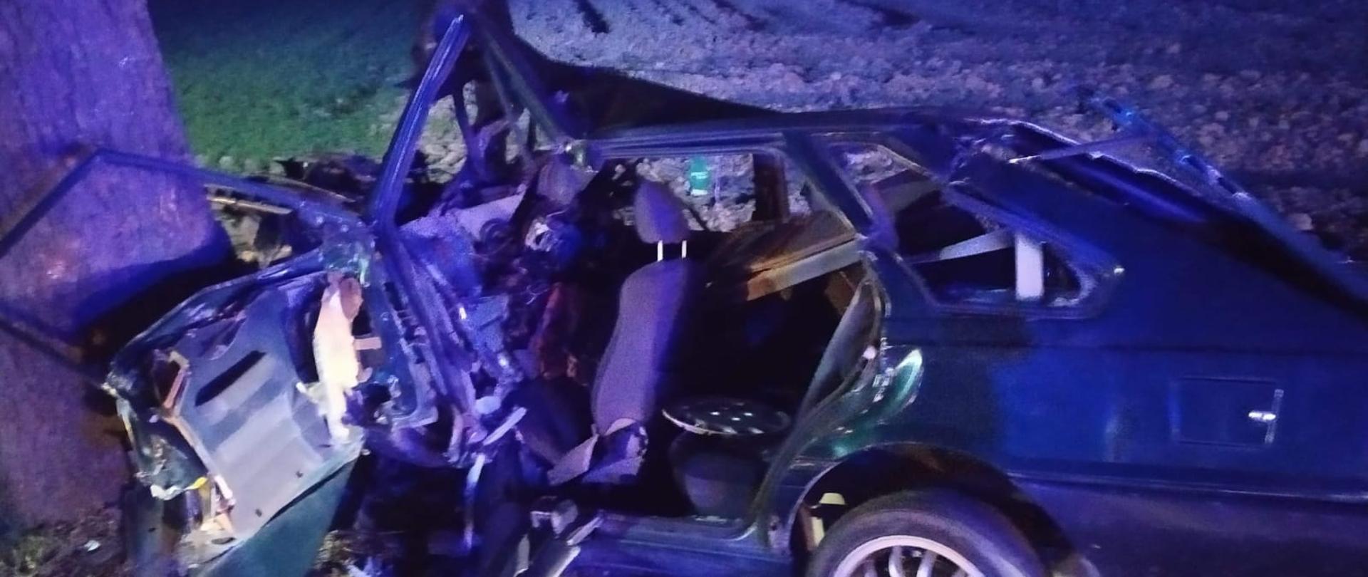 Widać uszkodzony samochód, który przodem uderzył w drzewo, bok od kierowcy uszkodzony