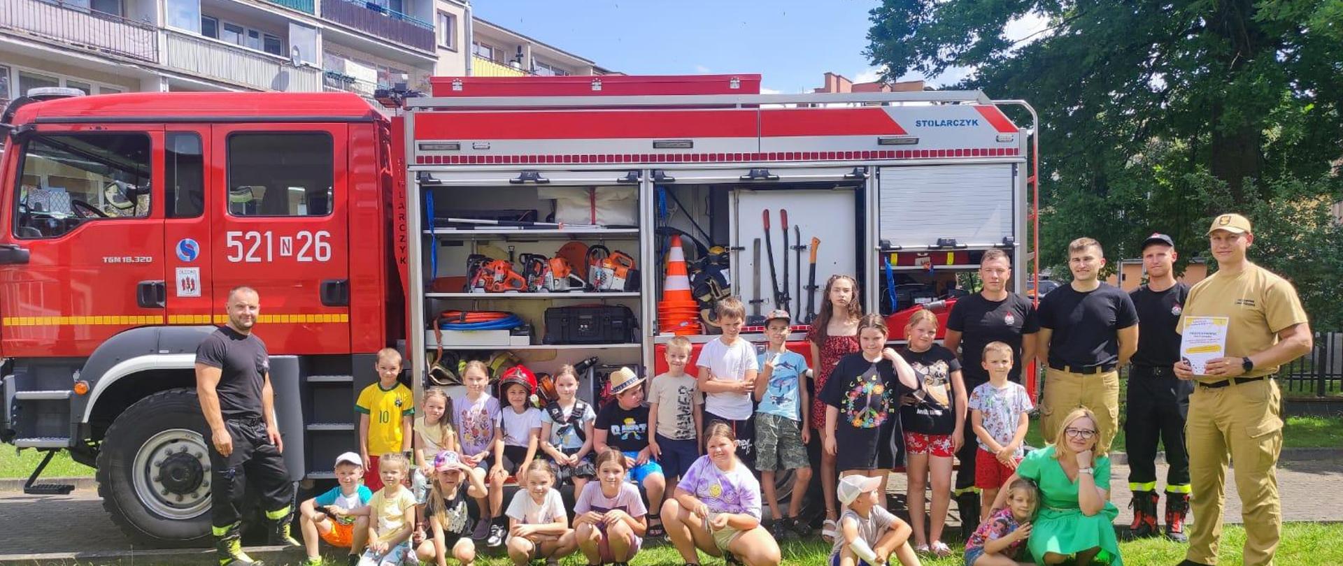 Pamiątkowe zdjęcie uczestników spotkania na tle samochodu.