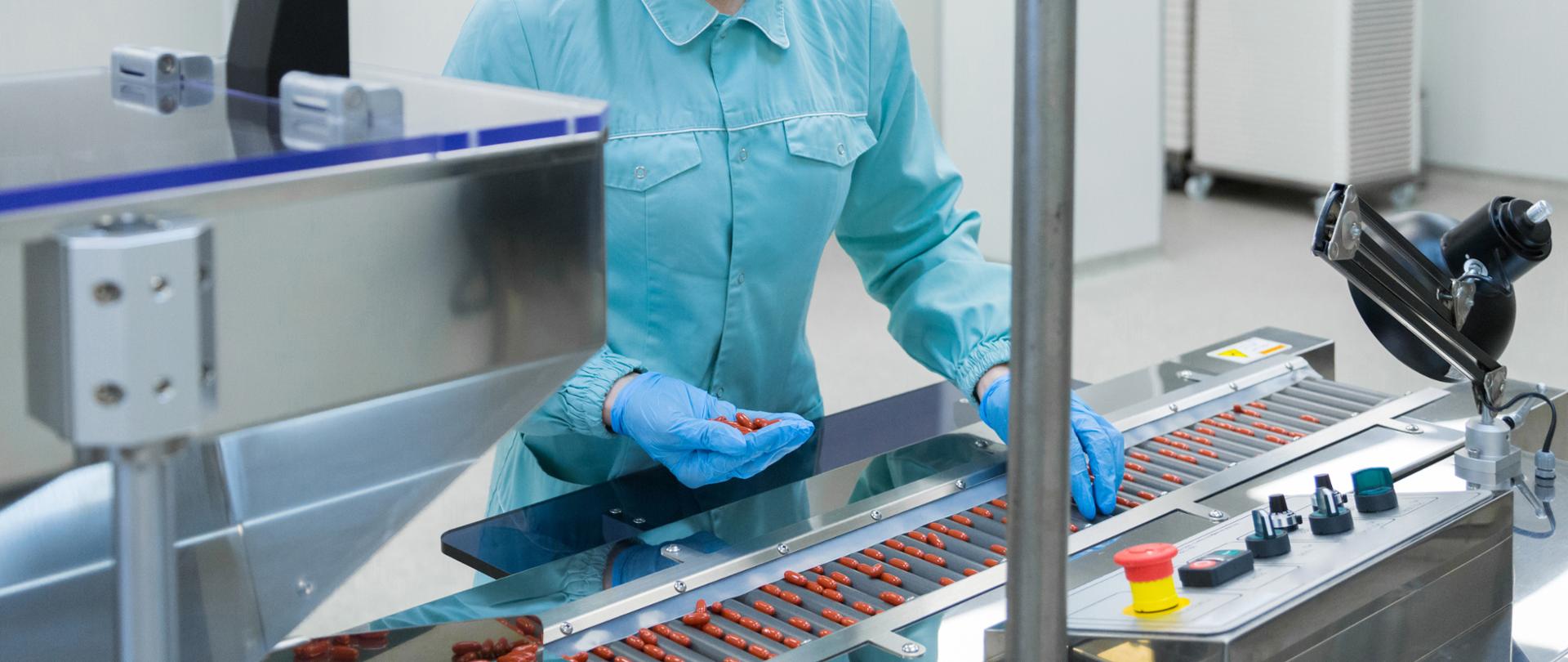 Technik farmaceutyczny w sterylnym środowisku pracujący przy produkcji tabletek w fabryce aptecznej