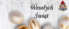 Zdjęcie przedstawia czarny napis Wesołych Świąt, w prawym górnym rogu logo Państwowej Straży Pożarnej. Na dole sześć pisanek w biało- złotym kolorze.