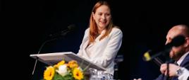Minister funduszy i polityki regionalnej Katarzyna Pełczyńska-Nałęcz stoi przy mównicy i przemawia, po jej lewej stronie stoi stół przy którym siedzi burmistrz Orzesza Mariusz Oleś