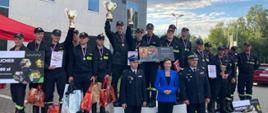 Na zdjęciu stojący na podium medaliści Mistrzostw Polski w ratownictwie technicznym. Przed podium stoi Śląski Komendant Wojewódzki PSP, po jego prawej stronie kobieta oraz oficer PSP