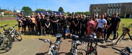 Zdjęcie grupowe strażaków biorących udział w rajdzie. Na pierwszym planie rowery, dalej strażacy i ich najbliżsi biorący udział w rajdzie.