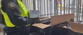 Funkcjonariusz SCS z zatrzymanymi paczkami nielegalnych e-papierosów