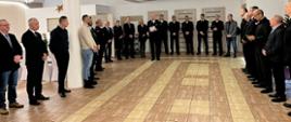 Zgromadzeni goście stoją na sali bankietowej w kręgu i wysłuchują przemówienia komendanta